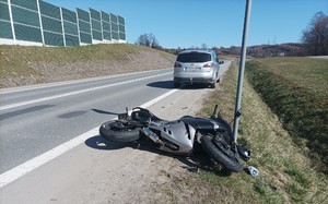 Kolizja motocykla z osobowym fordem. Na miejscu policja drogowa, oznakowany radiowóz z napisem Policja.