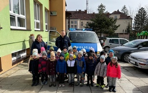 Na zdjęciu umundurowany policjant wraz z dziećmi z przedszkola. Policjant omówił zasady bezpieczeństwa w sieci i w ruchu drogowym.