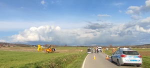 na zdjęciu widoczny  śmigłowiec lotniczego pogotowia ratunkowego. W zdarzeniu drogowym brał udział samochód osobowy i kierujący motocyklem. Policja i straż wykonywali czynności na miejscu wypadku.