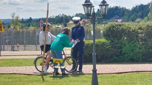 Uczestnik turnieju BRD zapoznający się z osiągniętym wynikiem po przejechaniu rowerem miasteczka ruchu drogowego i podpisujący u policjantki potwierdzenie o zapoznaniu się z nim.