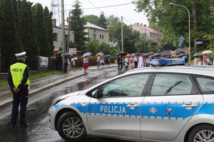 Policjant i radiowóz podczas zabezpieczenia przejścia procejsi.