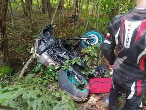 Widoczny motocykl, którym kierujący zjechał z drogi i uderzył w drzewo.