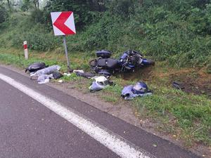 Widoczny wywrócony motocykl, który zjechał z drogi w miejscowości Domaradz oraz rozłożone na ziemi rzeczy motocyklisty i przewożonej pasażerki w tym dwa kaski.