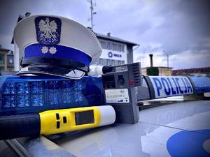 Na zdjęciu widać umieszczone na belce od radiowozu: czapkę policjanta ruchu drogowego, a przed nią ustawione na dachu radiowozu urządzenia do badania stanu trzeźwości typu: iBlow oraz Alkosensor, w tle rozmazany budynek Komendy Powiatowej Policji w Brzozowie